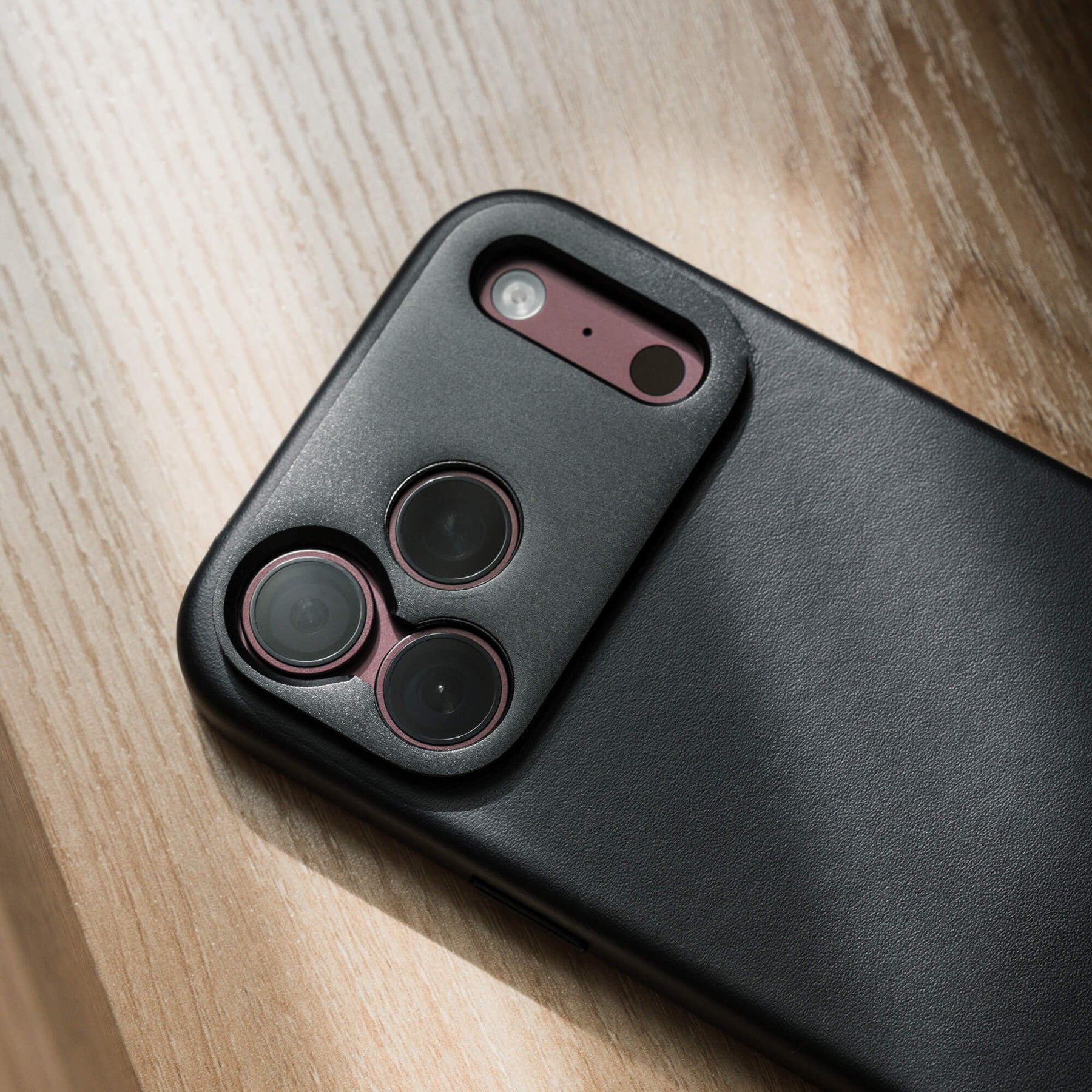 SANDMARC Pro Leather Case for iPhone 18 Pro in Black, close-up of camera cutout on a wooden surface.