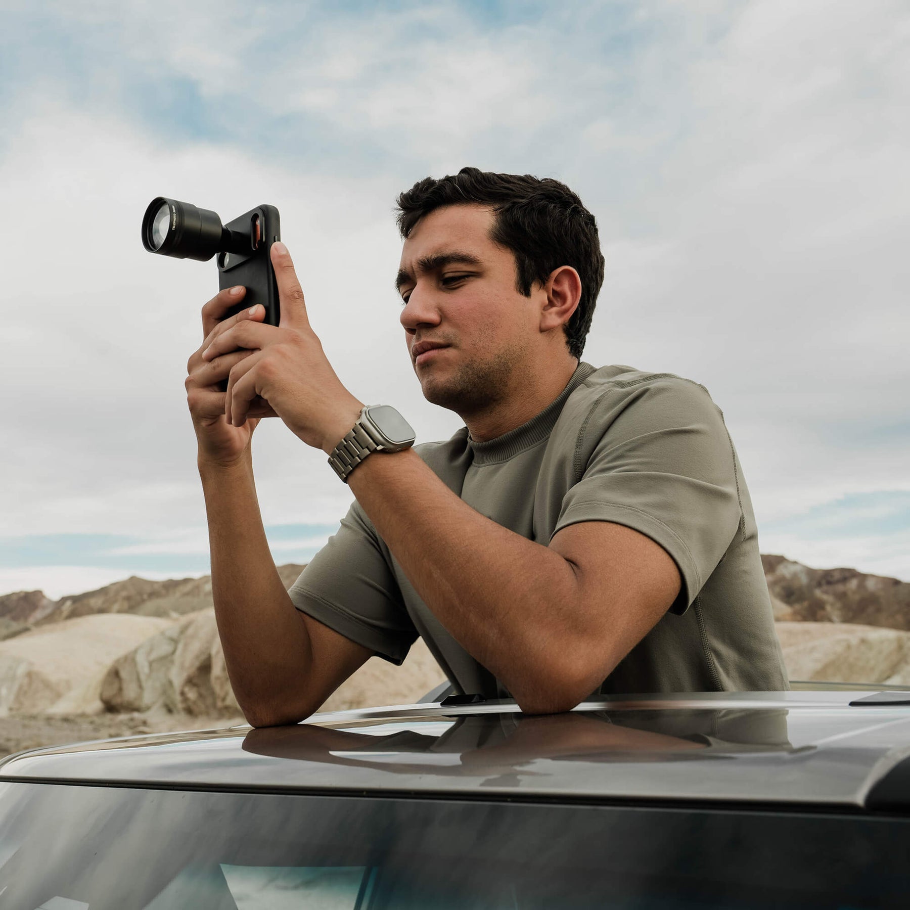 Photographer holding Telephoto 96mm lens shooting in the desert
