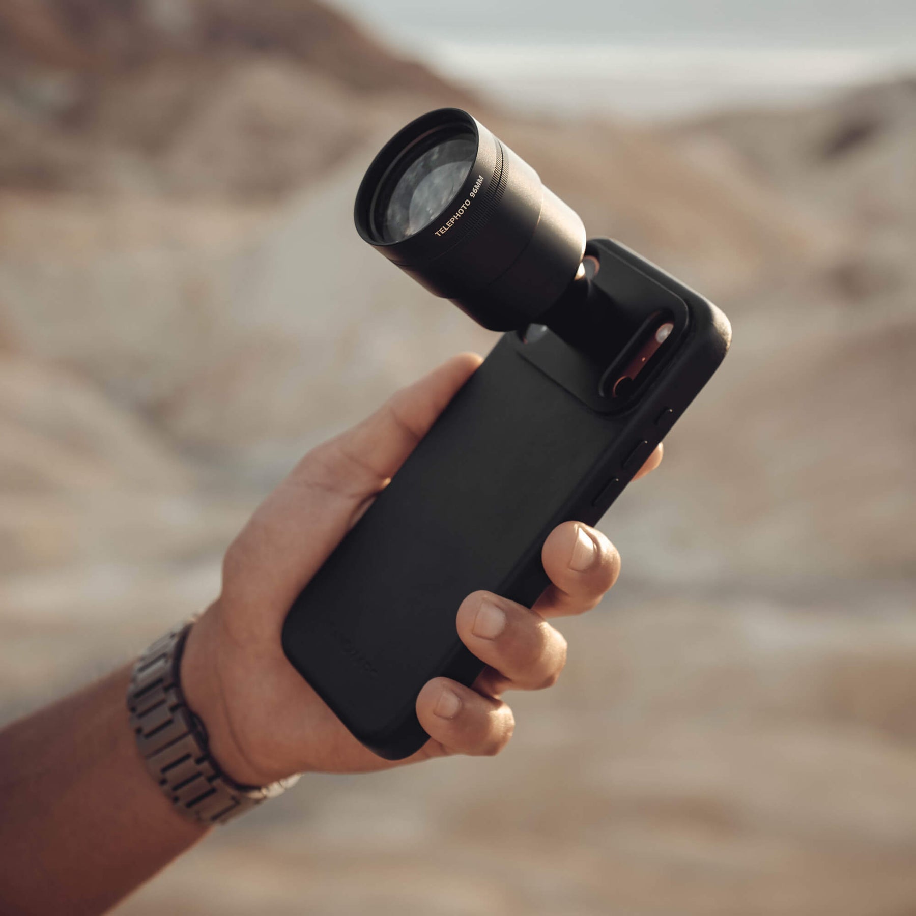 Telephoto 96mm Lens attached to black iPhone case in desert background