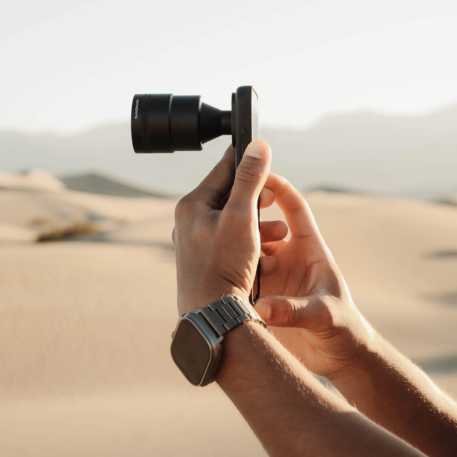 Telephoto 96mm Lens attached to black iPhone case side view with desert background