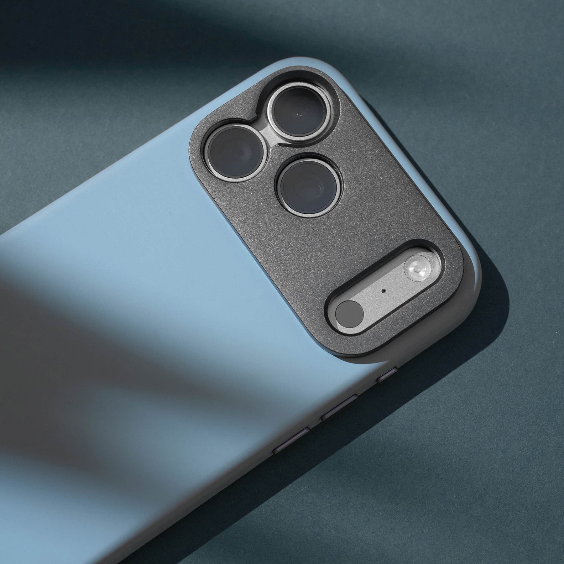 SANDMARC Pro Case for iPhone 18 Pro Max in Glacier blue, close-up of the camera cutout on a dark teal surface with shadow