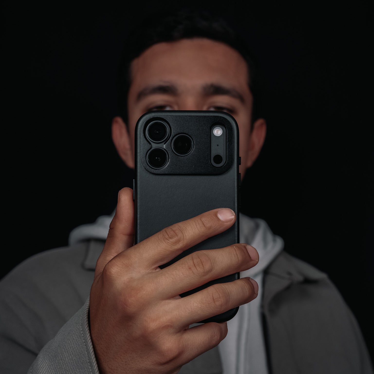 Man holding a Black Leather case for iPhone 18 Pro in Black Color